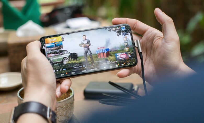 Close-up of hands holding smartphone displaying mobile game interface