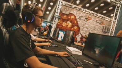 Professional esports tournament setup with multiple gaming stations and large screens displaying competition