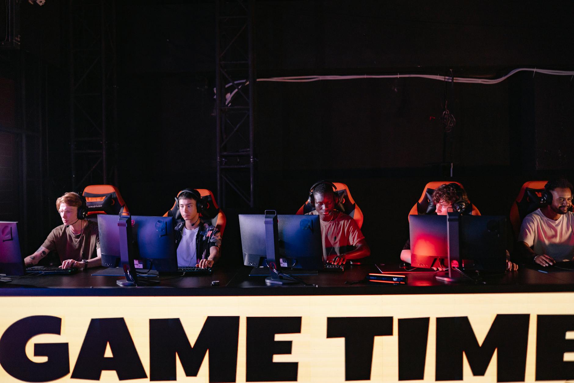 Professional esports tournament setup with gaming stations and large screens for competitive fighting game event