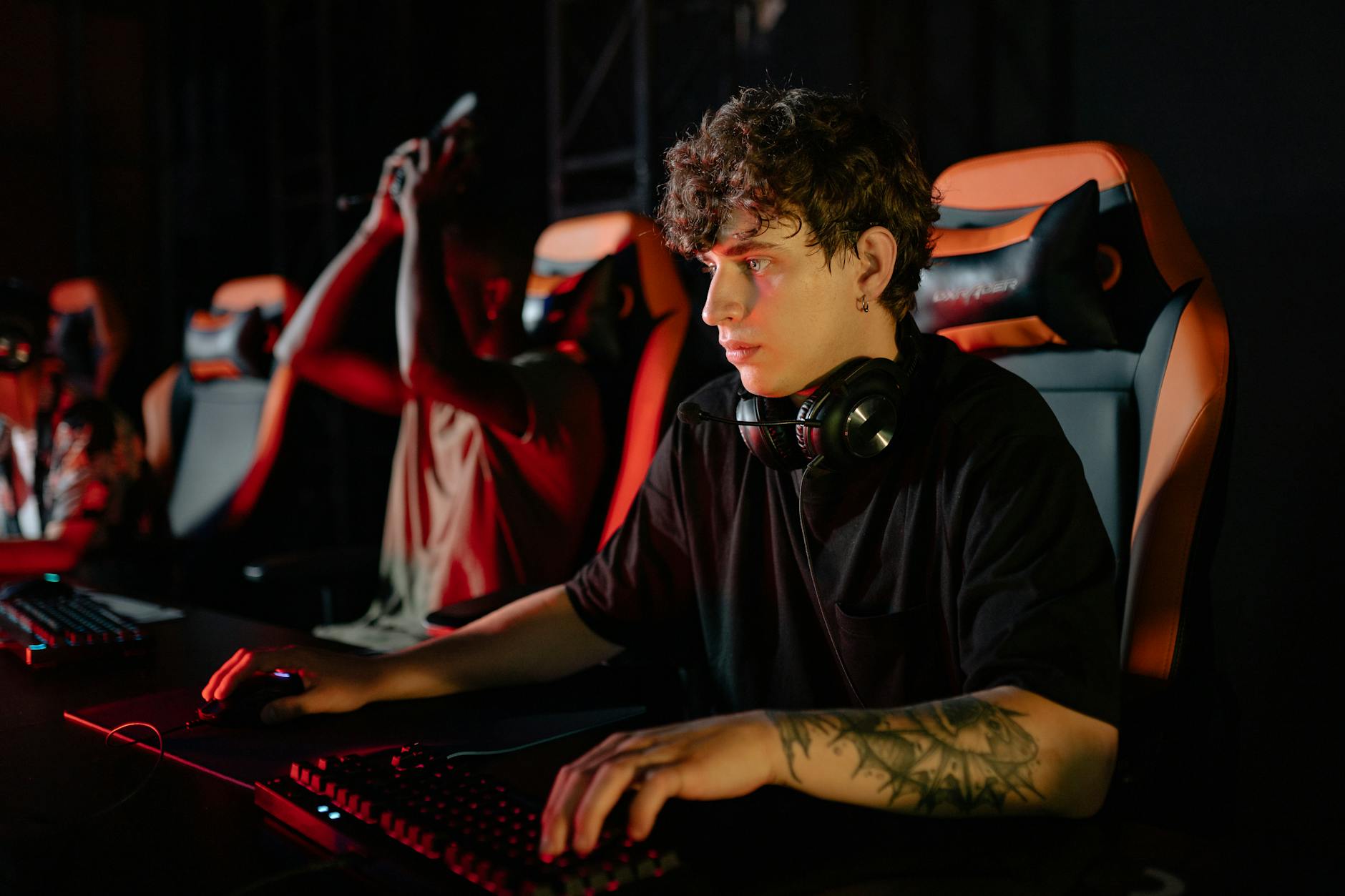 Professional esports tournament setup with players competing at gaming stations with monitors and equipment