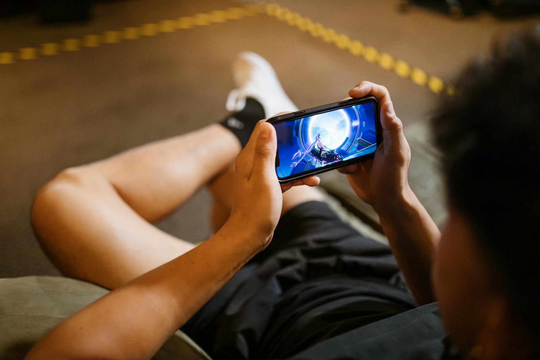 Person playing competitive mobile game on smartphone with focused concentration during tournament play