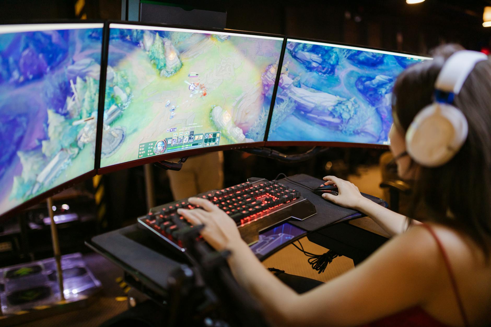 Three gaming monitors displaying cooperative multiplayer gameplay in a dark room