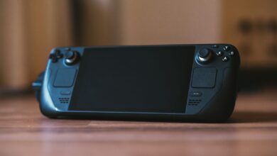 Handheld gaming PC held in two hands showing game running on screen