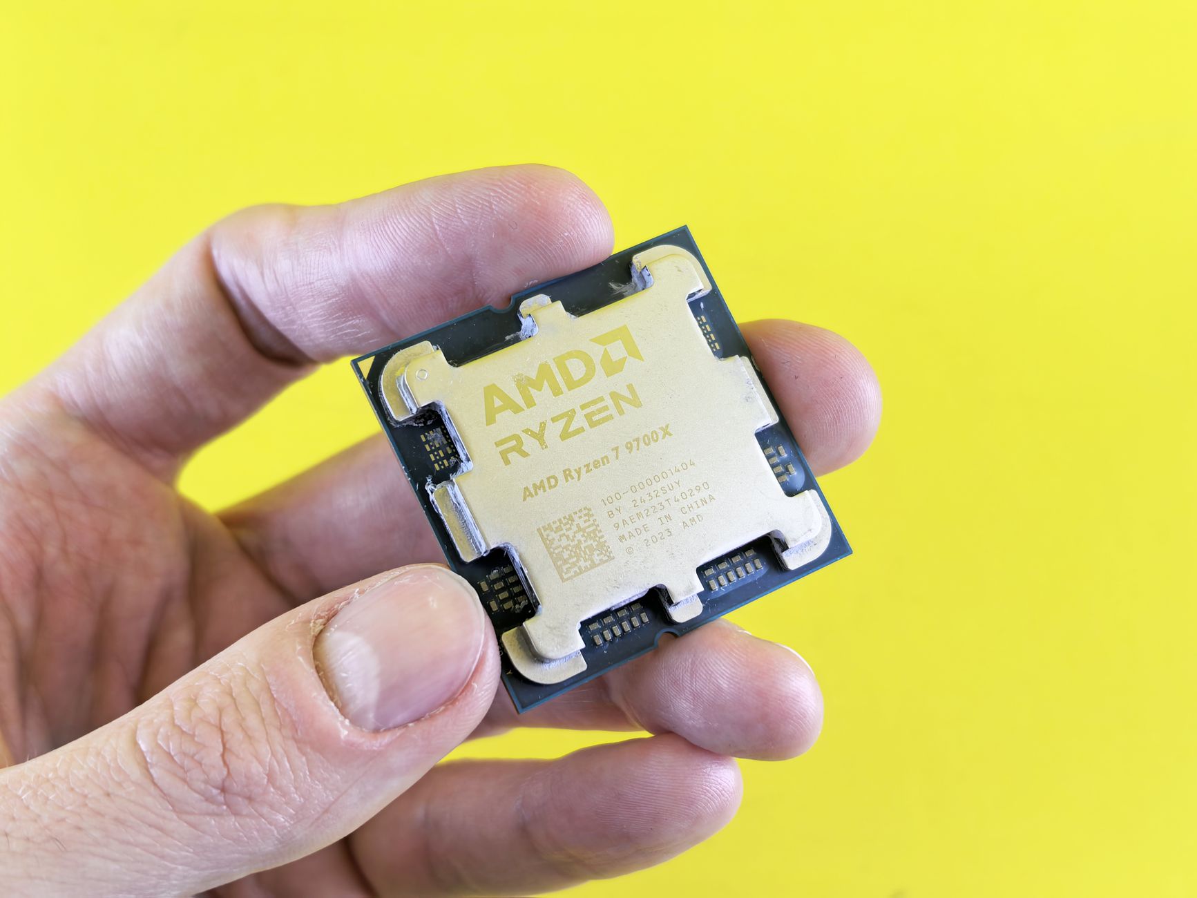 Modern desktop processor chip held above a motherboard showing contact pins